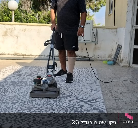 אדם מנקה שטיח עם מכונת ניקוי חשמלית